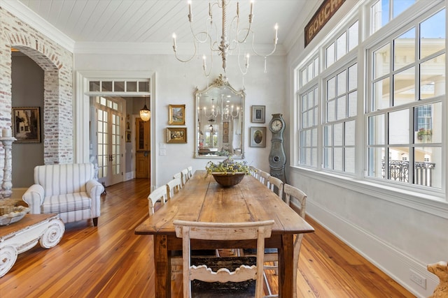 dining room with a healthy amount of sunlight, baseboards, a chandelier, and crown molding