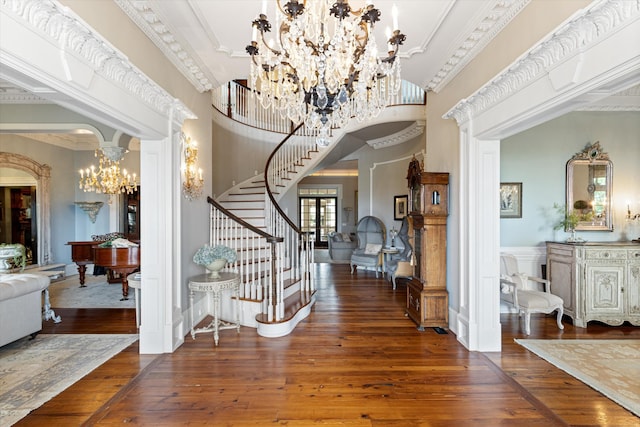 entrance foyer featuring stairs, ornamental molding, dark wood finished floors, and a notable chandelier