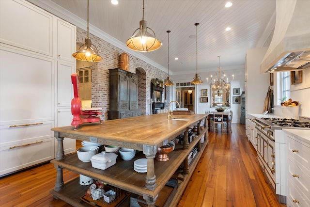 kitchen with pendant lighting, ornamental molding, custom exhaust hood, and white cabinets