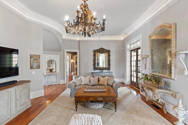 living area featuring crown molding, baseboards, and wood finished floors