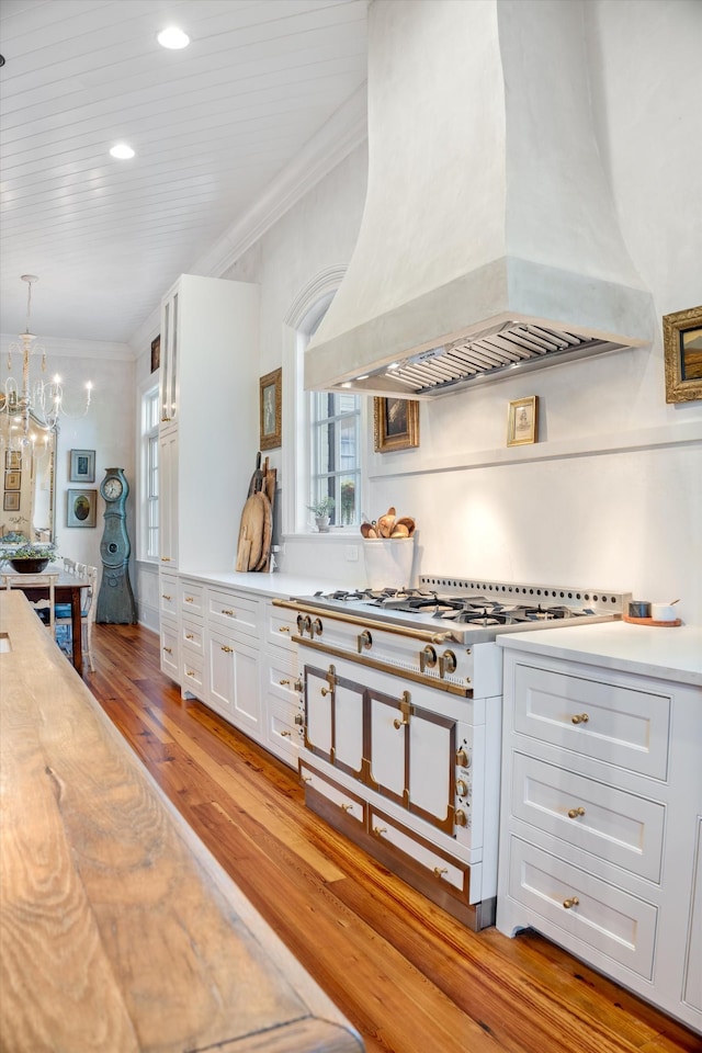 kitchen with ornamental molding, light countertops, custom range hood, and white cabinetry