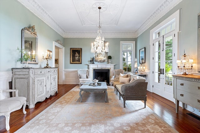 sitting room with a wainscoted wall, a fireplace, a decorative wall, an inviting chandelier, and wood finished floors