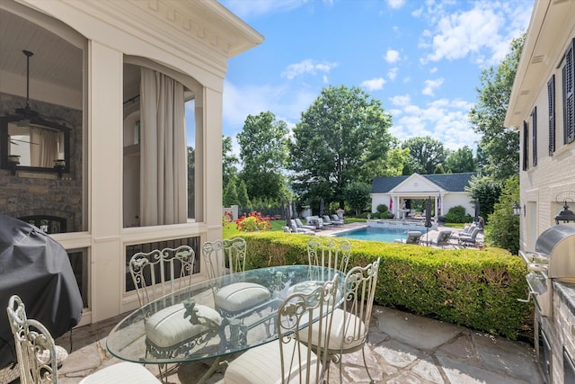 view of patio with outdoor dining space, a grill, and an outdoor pool