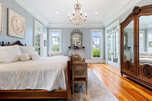 bedroom with light wood finished floors, multiple windows, crown molding, and an inviting chandelier