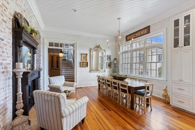 dining room with stairway, an inviting chandelier, ornamental molding, light wood-type flooring, and baseboards