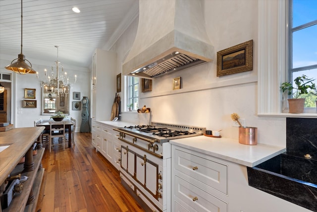 kitchen with white cabinets, custom range hood, light countertops, stainless steel gas stovetop, and pendant lighting