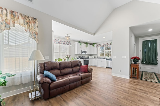 living room featuring high vaulted ceiling, recessed lighting, light wood-style flooring, and baseboards