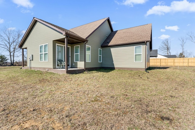 back of property with roof with shingles, a lawn, and fence