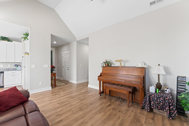 living room featuring light wood-type flooring, high vaulted ceiling, baseboards, and visible vents