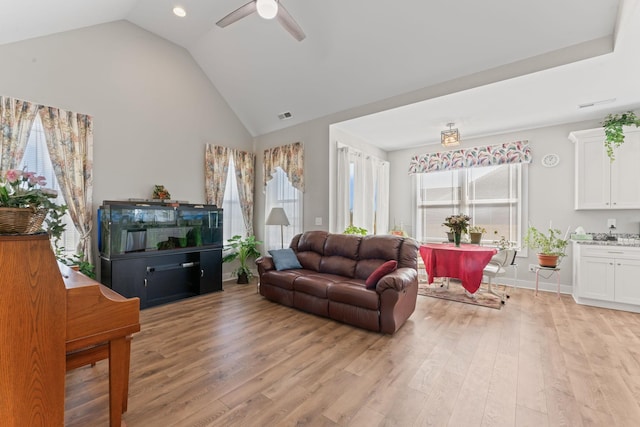 living area featuring visible vents, light wood finished floors, a wealth of natural light, and a ceiling fan