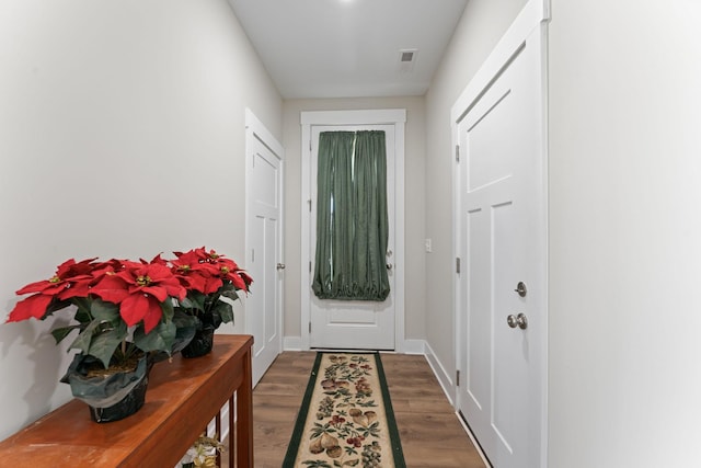 doorway to outside featuring wood finished floors, visible vents, and baseboards