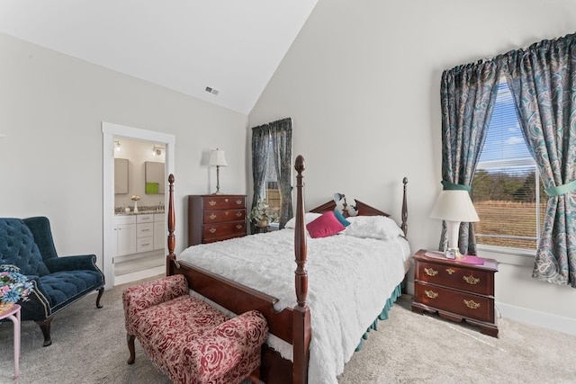 bedroom with ensuite bathroom, high vaulted ceiling, baseboards, and light colored carpet