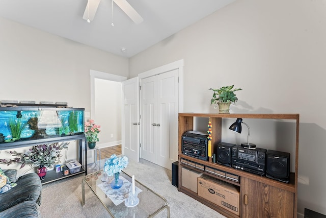 living room with ceiling fan, baseboards, and light colored carpet