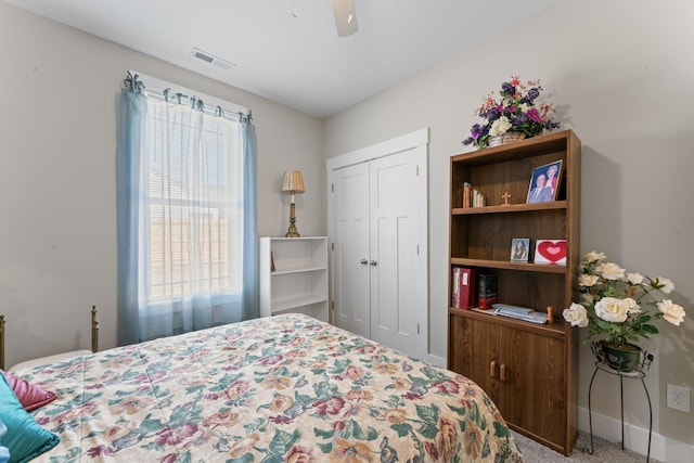 carpeted bedroom featuring a ceiling fan, a closet, visible vents, and baseboards