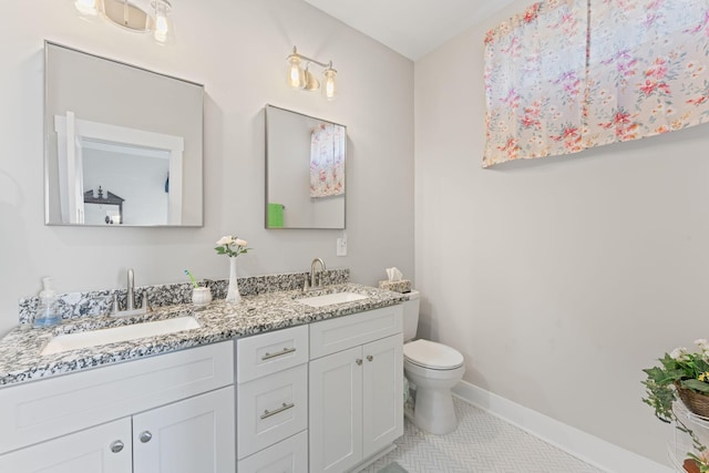 bathroom with toilet, a sink, baseboards, and double vanity