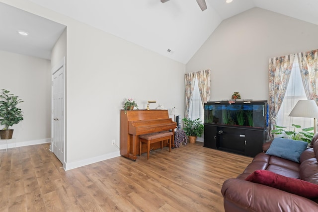 living room featuring baseboards, visible vents, a ceiling fan, light wood-type flooring, and high vaulted ceiling