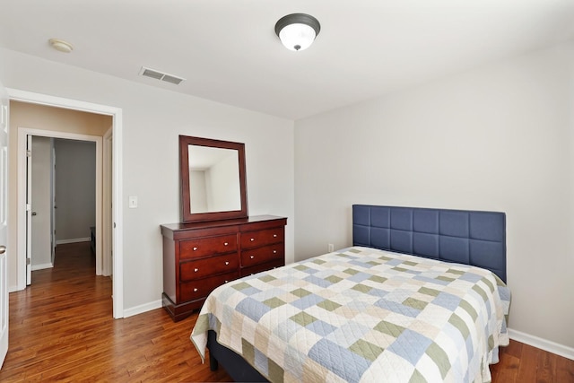 bedroom with visible vents, baseboards, and wood finished floors