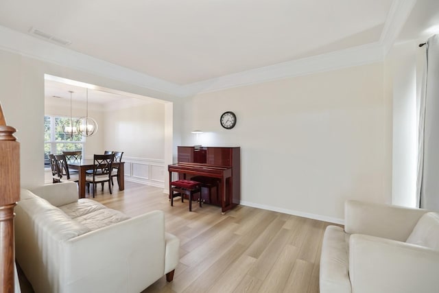 living area with light wood-style flooring, visible vents, a decorative wall, and ornamental molding