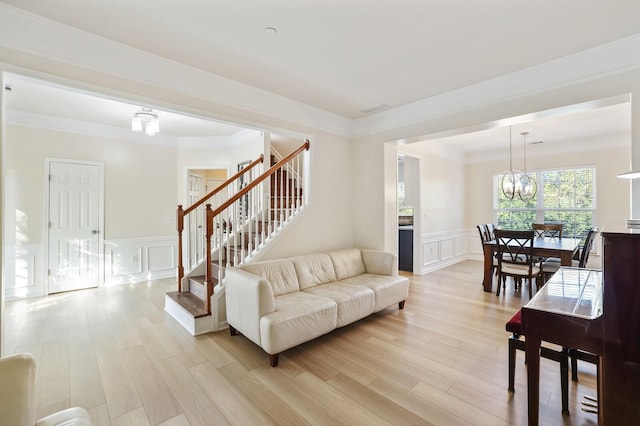 living room featuring light wood-style floors, a chandelier, a decorative wall, and stairs