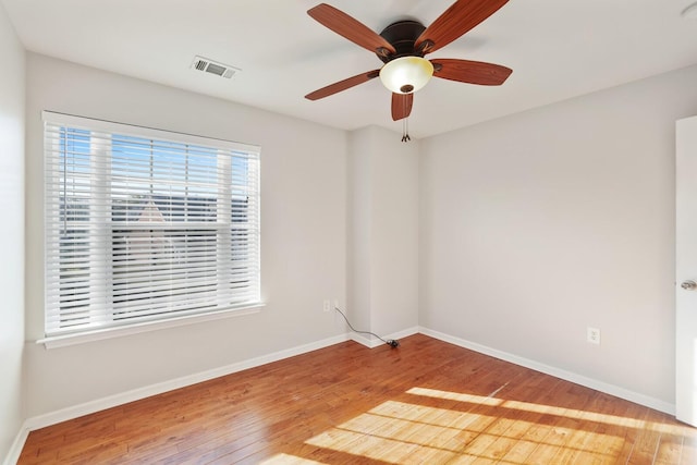 unfurnished room with a ceiling fan, visible vents, baseboards, and wood finished floors