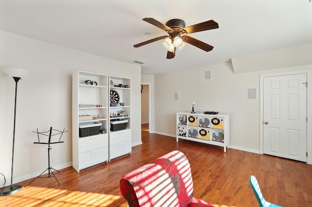 living area with baseboards, visible vents, and wood finished floors