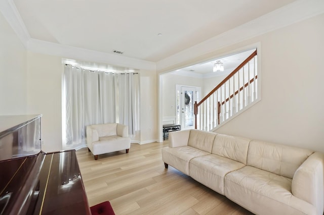 living area featuring baseboards, visible vents, crown molding, and light wood finished floors