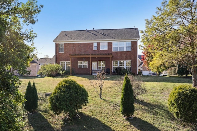 back of property featuring brick siding and a yard