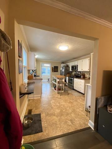 kitchen featuring appliances with stainless steel finishes, white cabinets, and crown molding