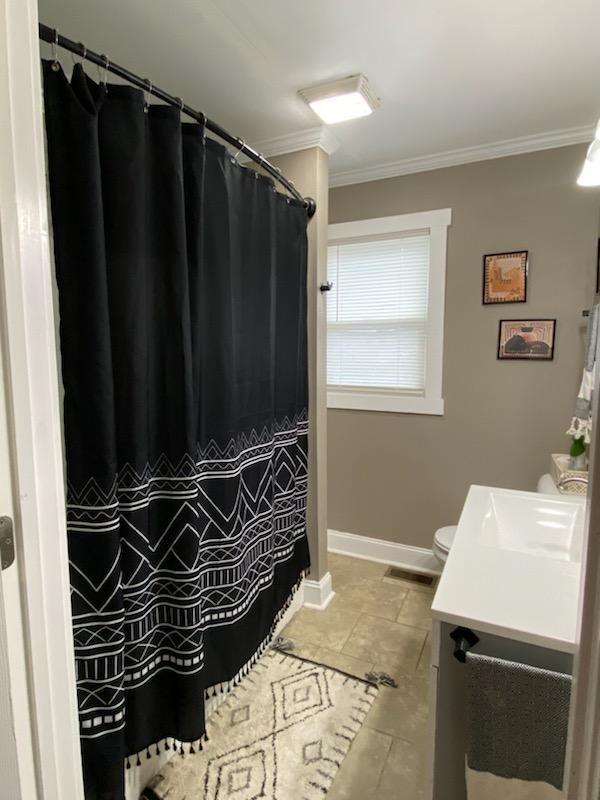 bathroom featuring toilet, baseboards, crown molding, and vanity