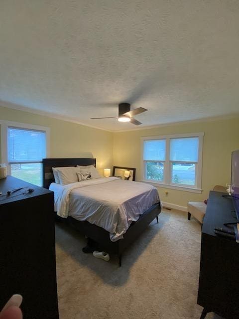 carpeted bedroom featuring a ceiling fan, crown molding, a textured ceiling, and baseboards