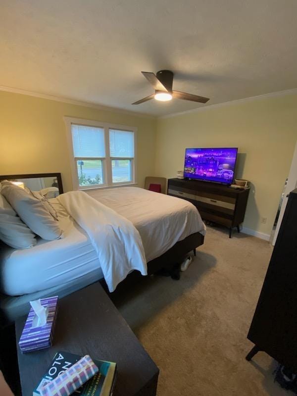 carpeted bedroom with ceiling fan, ornamental molding, and baseboards