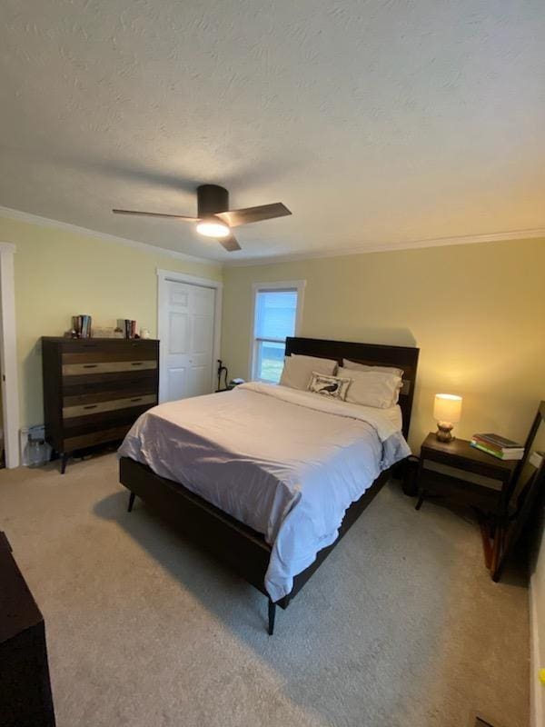 bedroom featuring crown molding, a closet, a ceiling fan, carpet flooring, and a textured ceiling