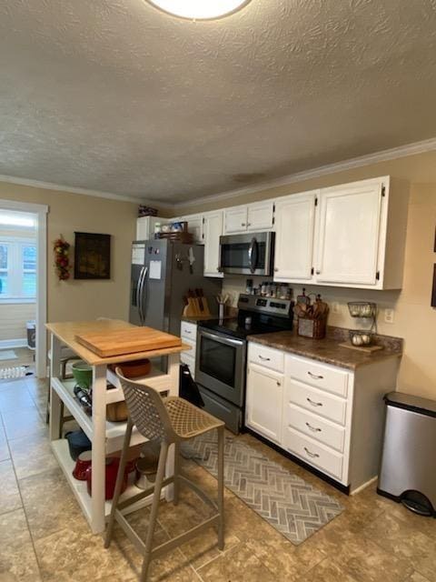 kitchen featuring ornamental molding, appliances with stainless steel finishes, dark countertops, and white cabinetry