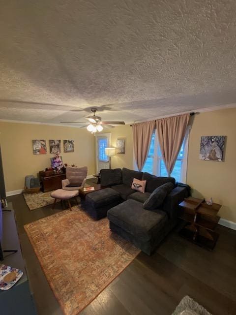 living room with ceiling fan, a textured ceiling, baseboards, and wood finished floors