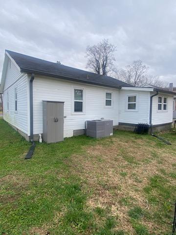 rear view of house featuring a lawn and central AC