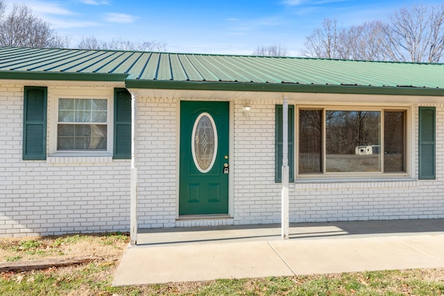 view of exterior entry featuring brick siding and metal roof