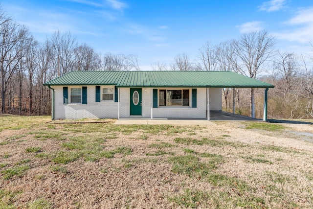 ranch-style house with driveway, metal roof, an attached carport, covered porch, and brick siding