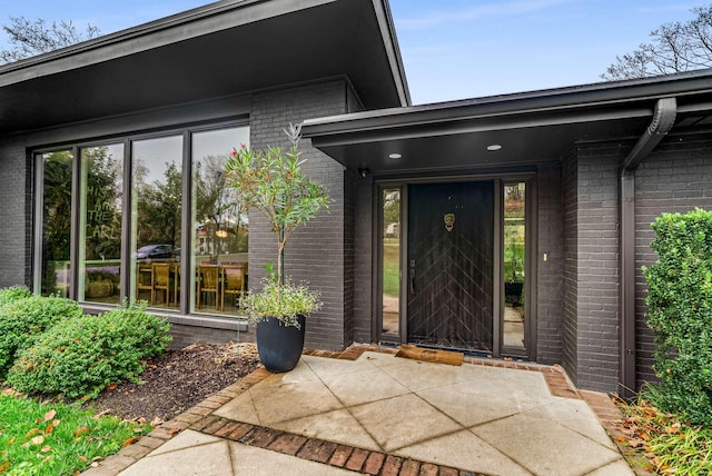 property entrance featuring a patio and brick siding