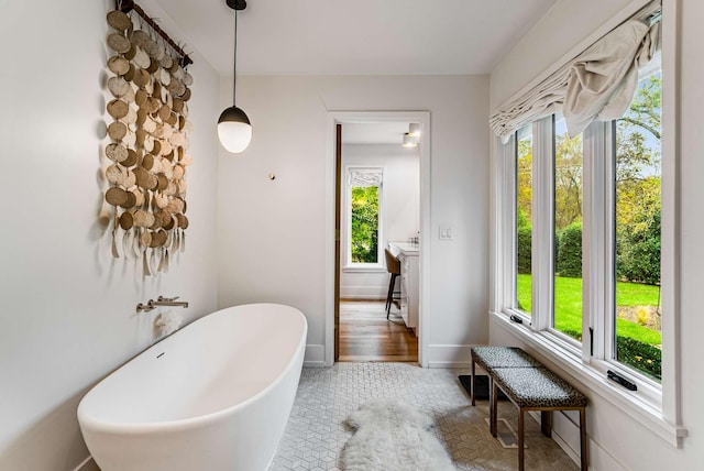 bathroom with a freestanding bath, tile patterned floors, a wealth of natural light, and baseboards