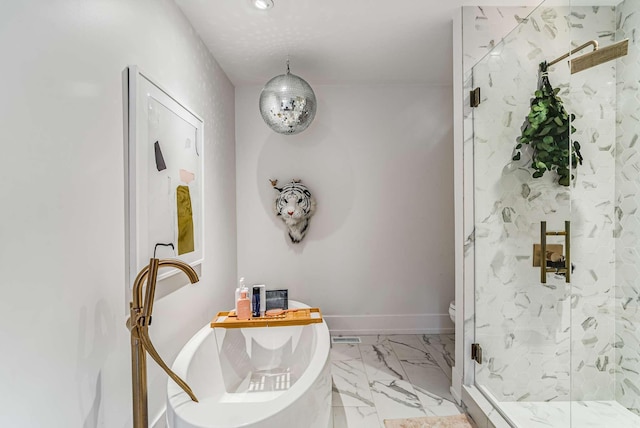 bathroom with marble finish floor, a marble finish shower, baseboards, and a freestanding tub