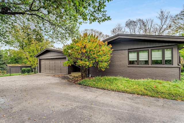 view of front of home featuring a garage, fence, board and batten siding, and brick siding