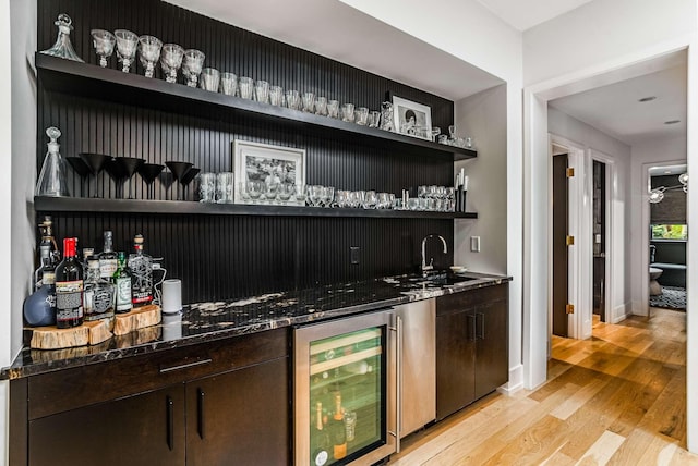 bar with baseboards, light wood-style flooring, wine cooler, wet bar, and a sink