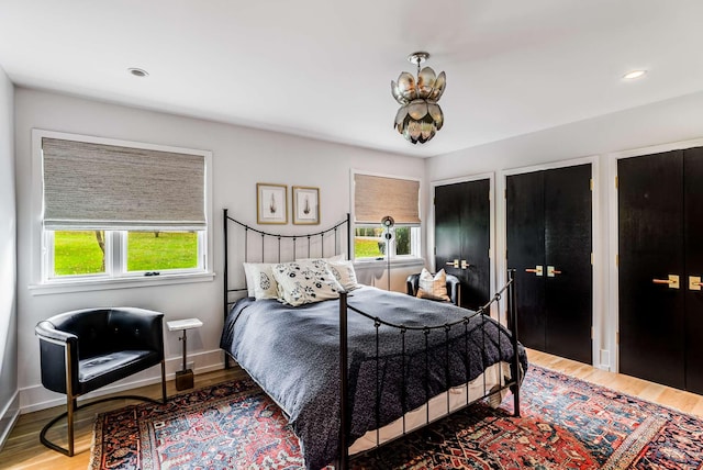 bedroom with multiple closets, recessed lighting, baseboards, and wood finished floors