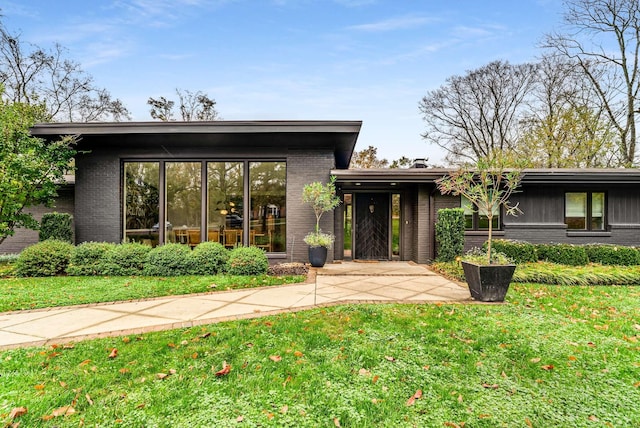 mid-century modern home with a front yard and brick siding