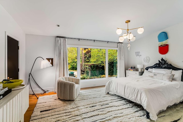 bedroom with a notable chandelier, baseboards, and wood finished floors