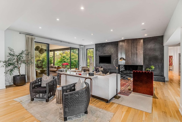 living area featuring a large fireplace, recessed lighting, and light wood-style floors