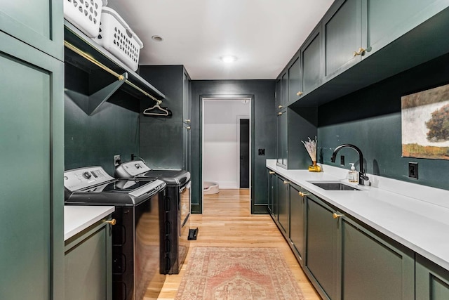 laundry area featuring cabinet space, washing machine and dryer, light wood-style flooring, and a sink