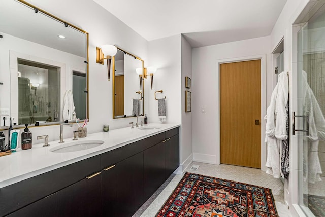 full bathroom with double vanity, a stall shower, a sink, and baseboards