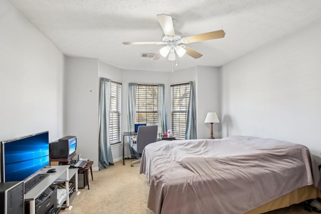 bedroom with a textured ceiling, a ceiling fan, visible vents, and light colored carpet