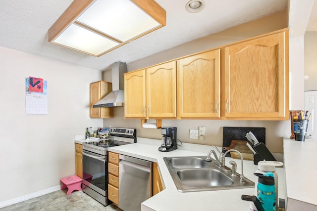 kitchen with light countertops, appliances with stainless steel finishes, light brown cabinets, a sink, and wall chimney exhaust hood